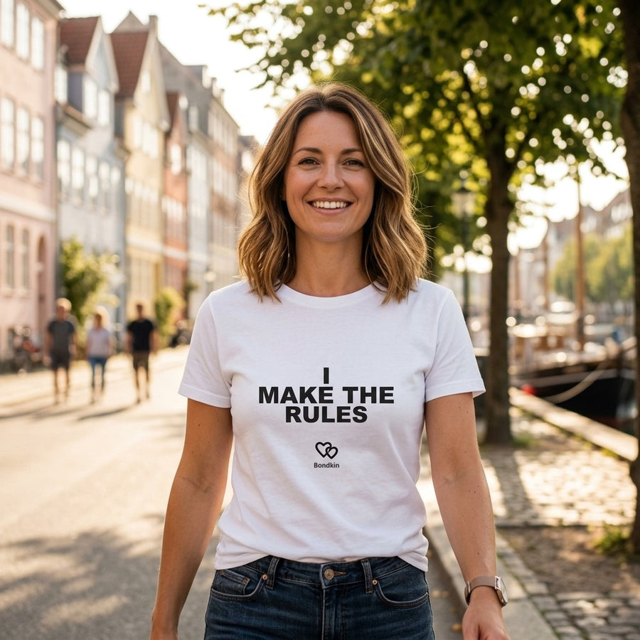 Smiling woman in a white Bondkin I make the rules tee on a sunny street