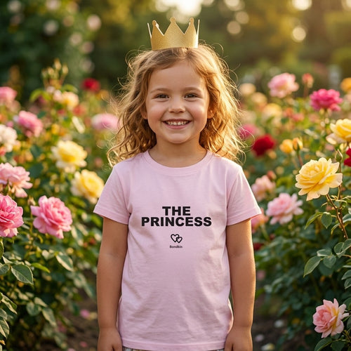 Girl in a pink Bondkin The Princess tee and a paper crown among roses