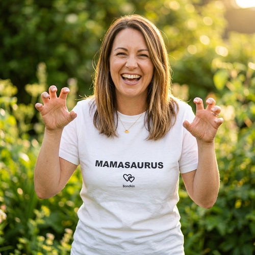 Laughing woman in a white Bondkin Mamasaurus tee making dinosaur claws